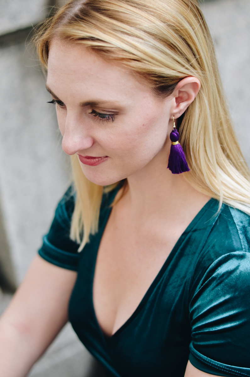 At New York Fashion Week wearing an emerald velvet dress and purple tassel earrings