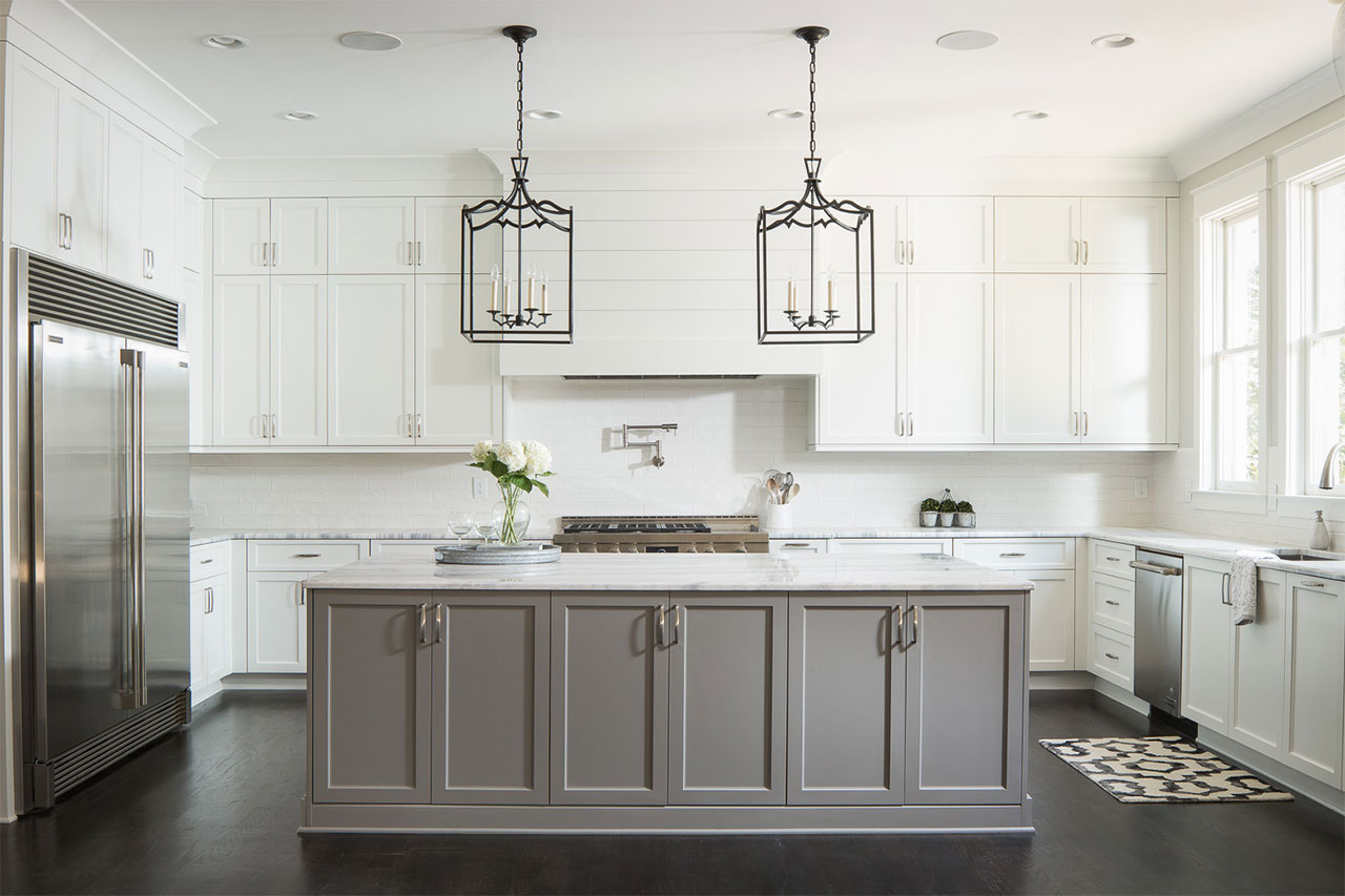 Gorgeous chandeliers hang over a spacious island with a natural stone countertop for a chic, modern kitchen.