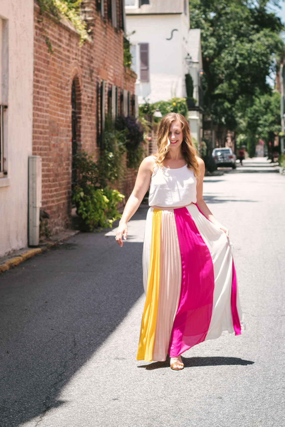 Easy summer outfit: Fashion blogger Allyn Lewis pairs a color blocked pleated skirt with a fresh white cami for an effortless look while exploring Charleston, SC.