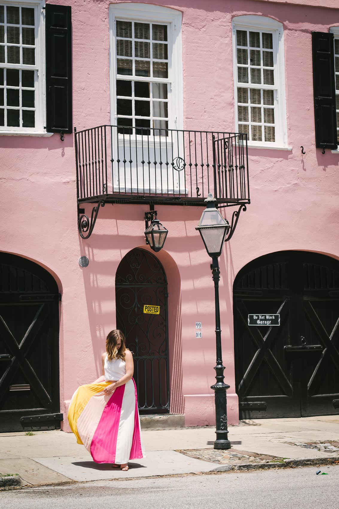 Easy summer outfit: Fashion blogger Allyn Lewis pairs a color blocked pleated skirt with a fresh white cami for an effortless look while exploring Charleston, SC and walking down Rainbow Row. 