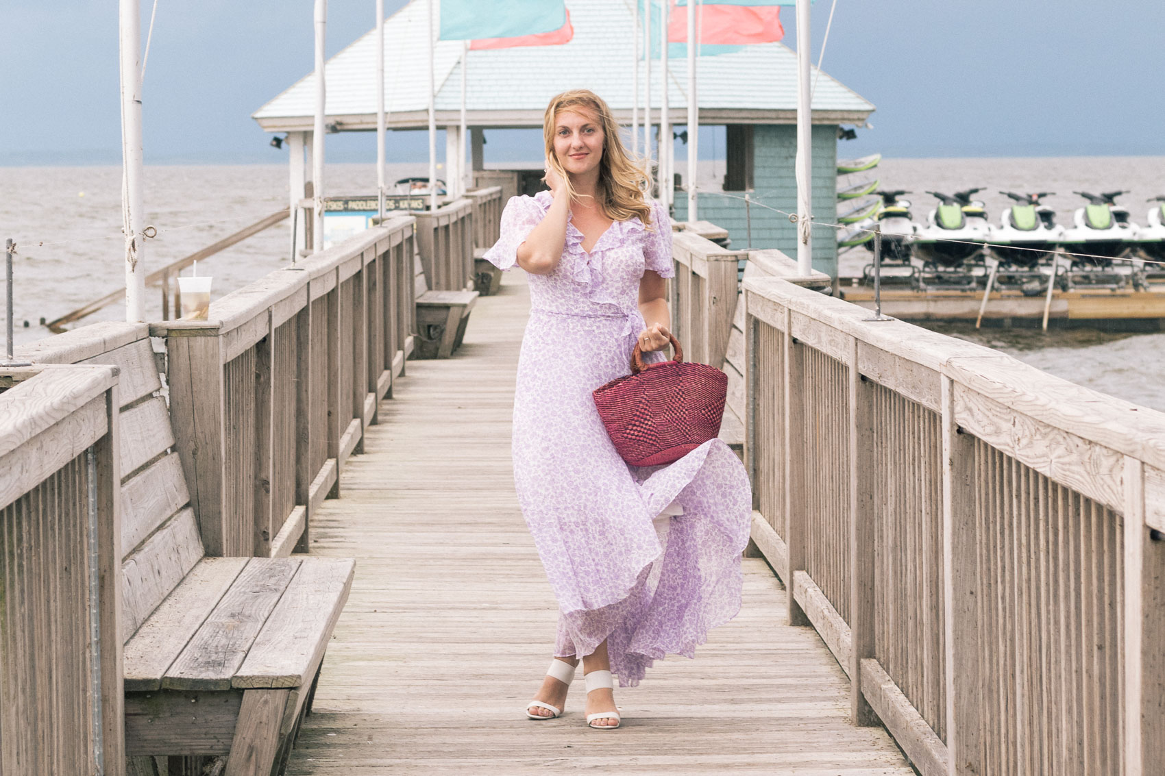 Allyn Lewis styles a purple faux wrap Gal Meets Glam Collection dress with block heels and a pink woven bag while on vacation in the Outer Banks, NC. 