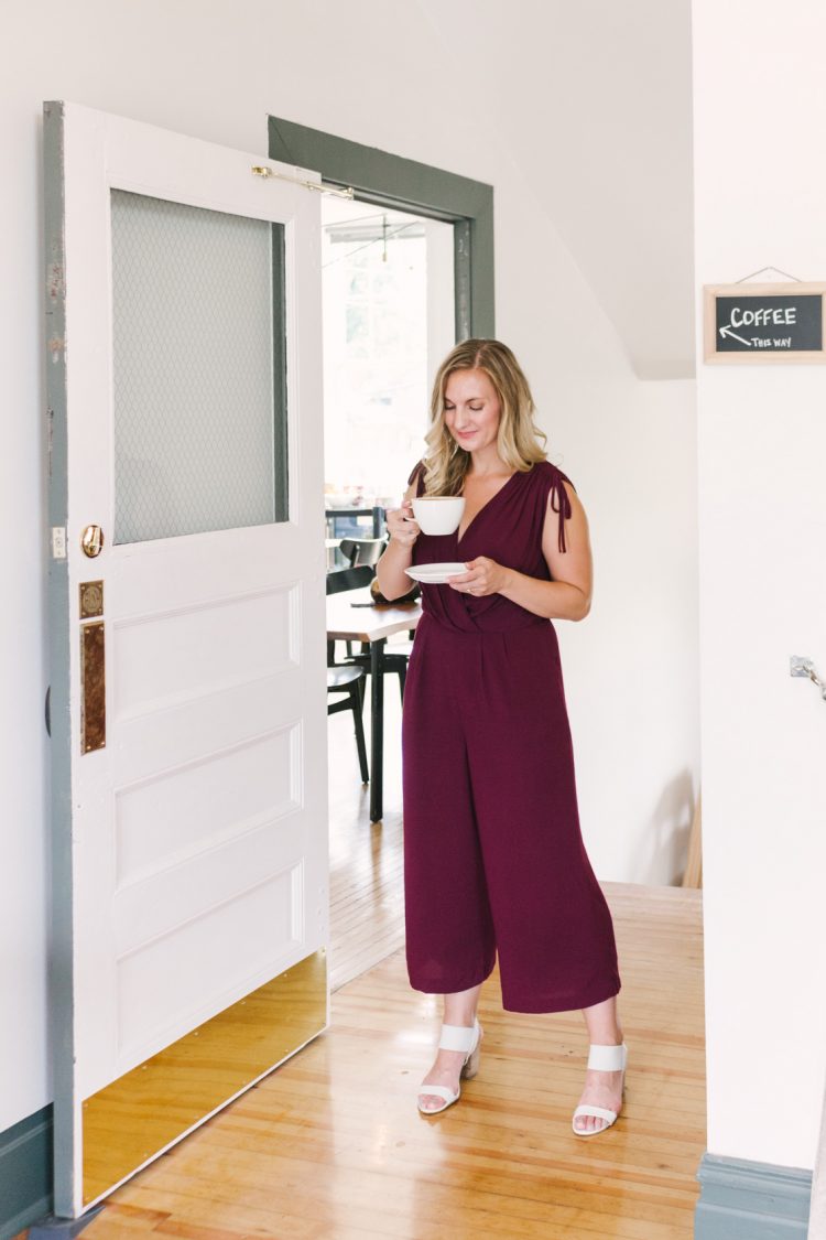 Allyn Lewis of The Gem styles a surplice oxblood casual jumpsuit as a classy summer to fall transitional outfit for a coffee date at Reginald's Coffee in Pittsburgh, PA. 