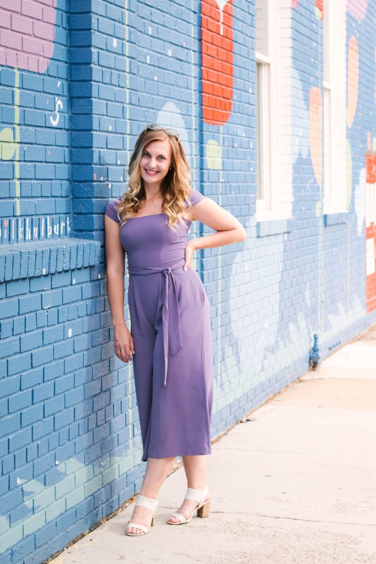 a casual purple jumpsuit styled with block heeled sandals for a casual spring outfit