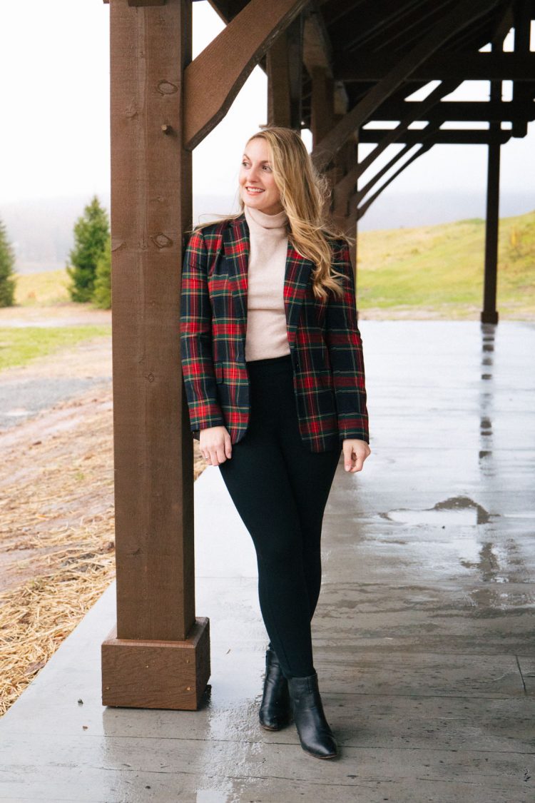 woman black leggings for work with a cream turtleneck sweater, plaid blazer, and black ankle boots