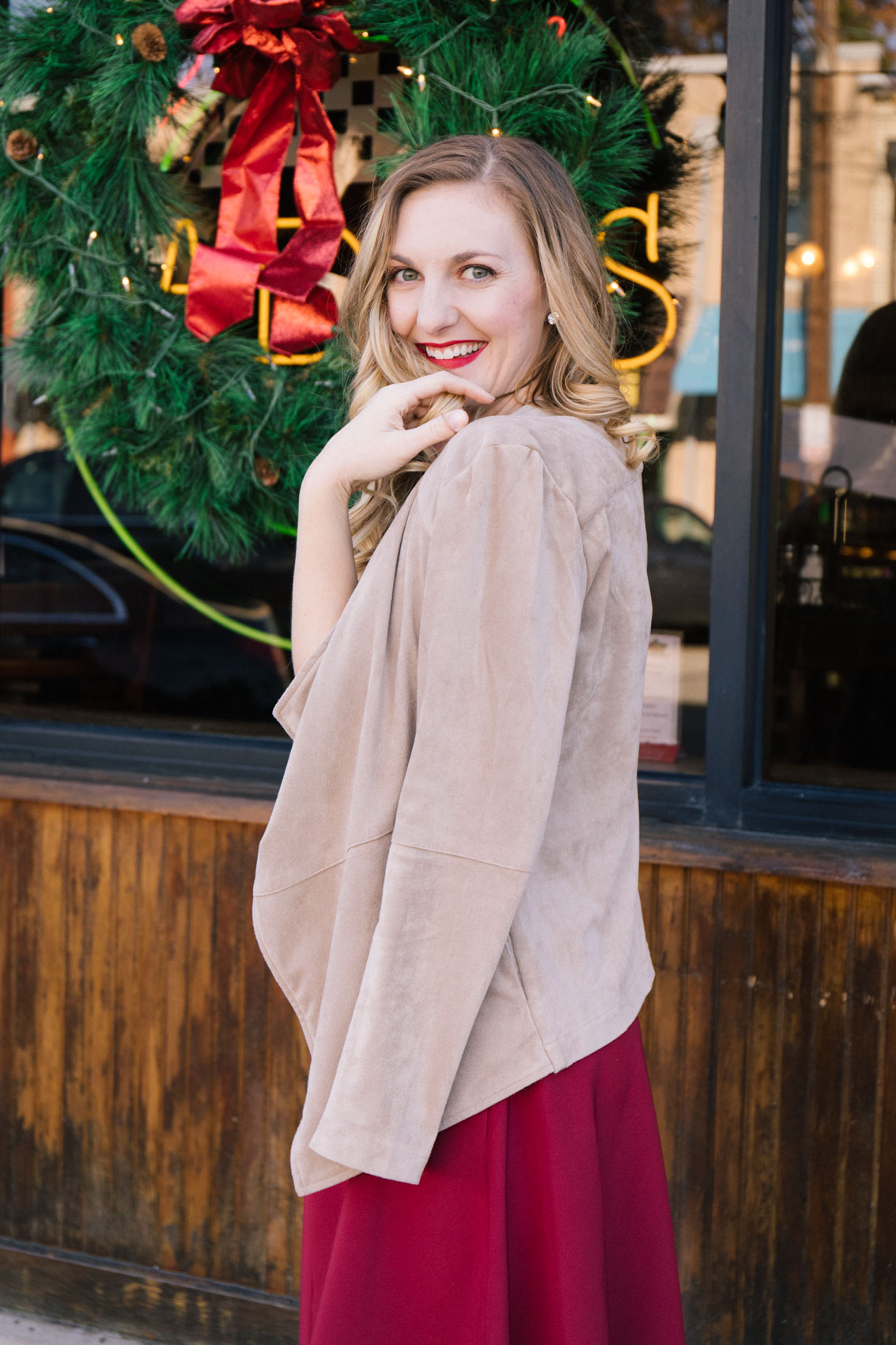 Tan faux suede jacket styled over a red dress for a classy winter outfit