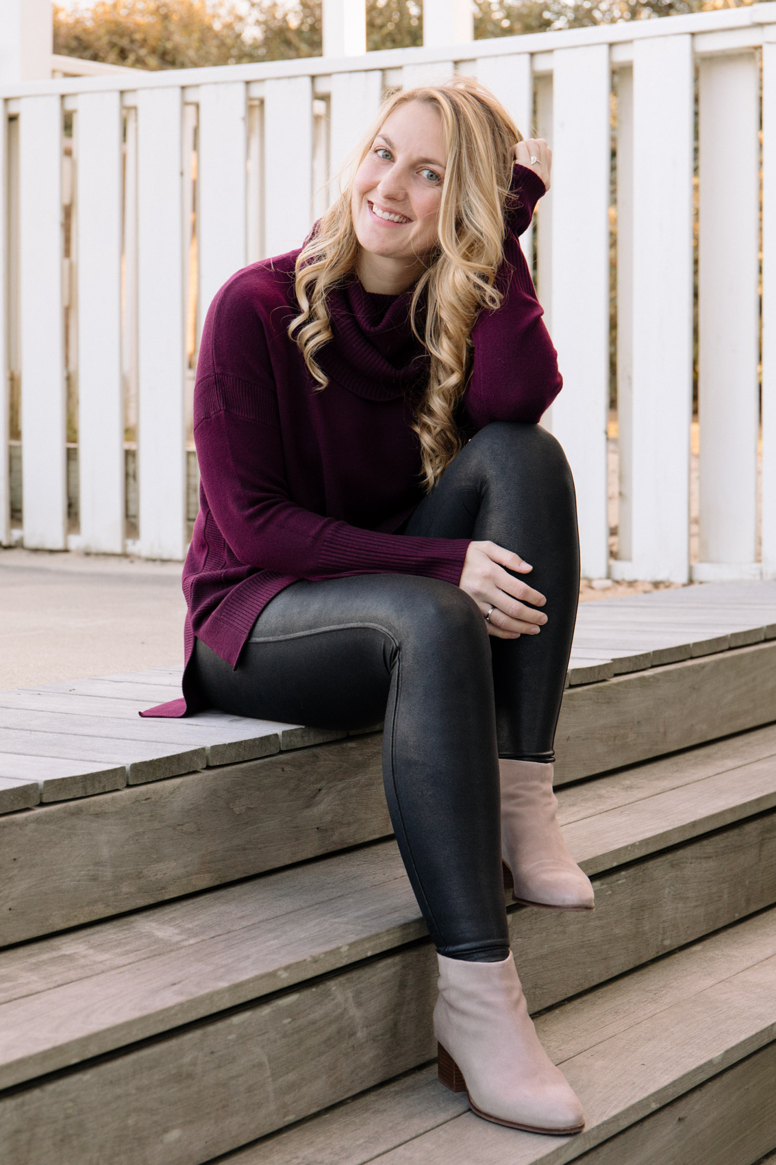 black Spanx faux leather leggings styled with a long purple sweater and ankle boots. 