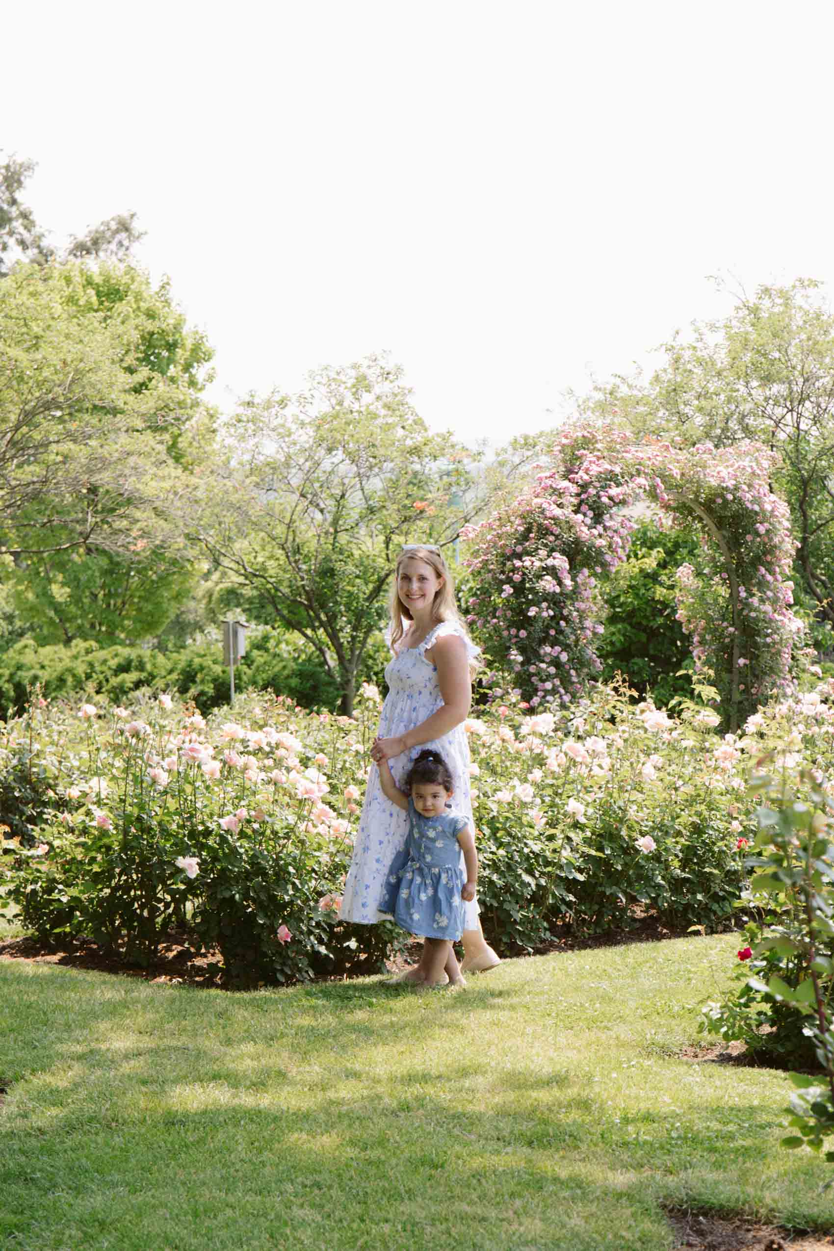 Women wearing a white dress walking a toddler through Hershey Gardens