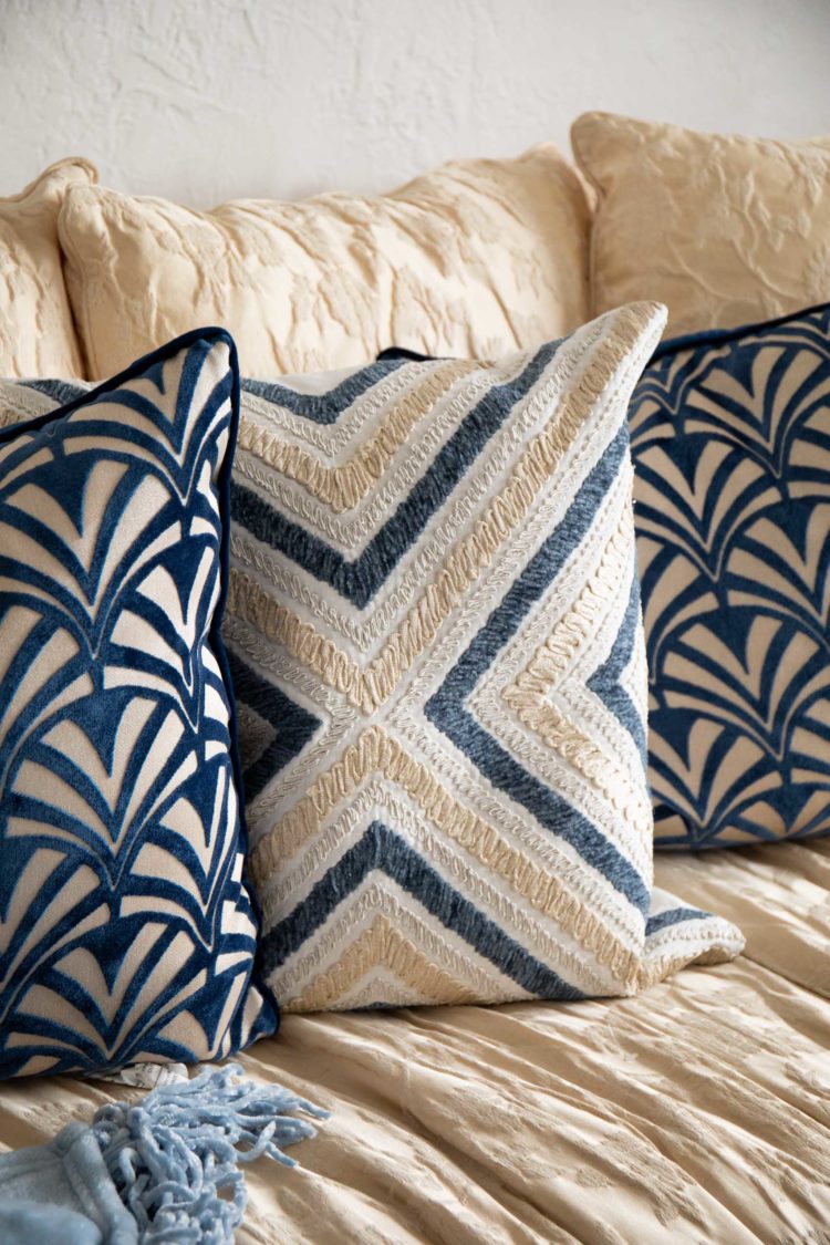 textured pillows with blue, cream, white, and grey on an off white sofa
