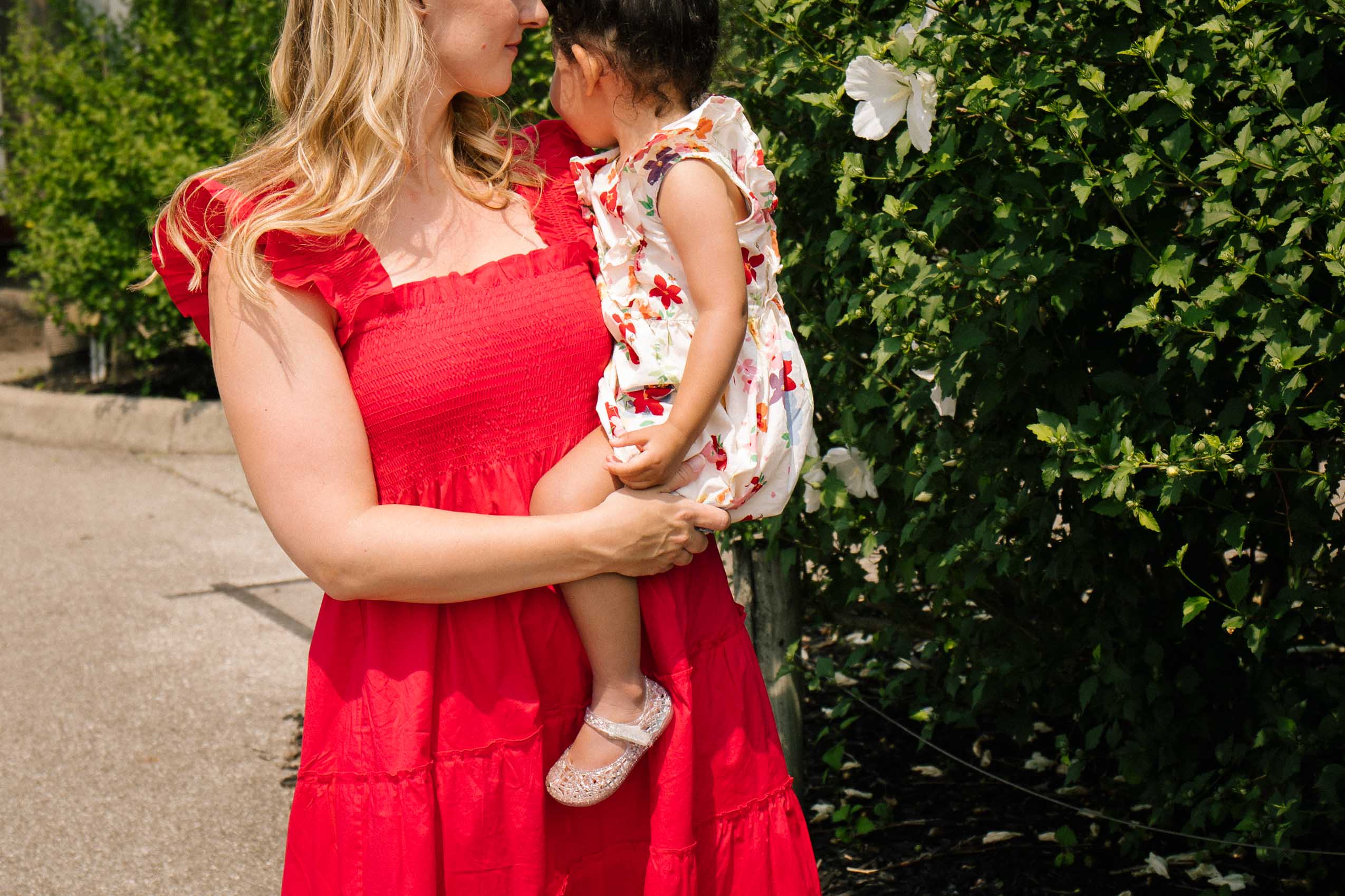 woman wearing a sleeveless red nap dress while holding a toddler