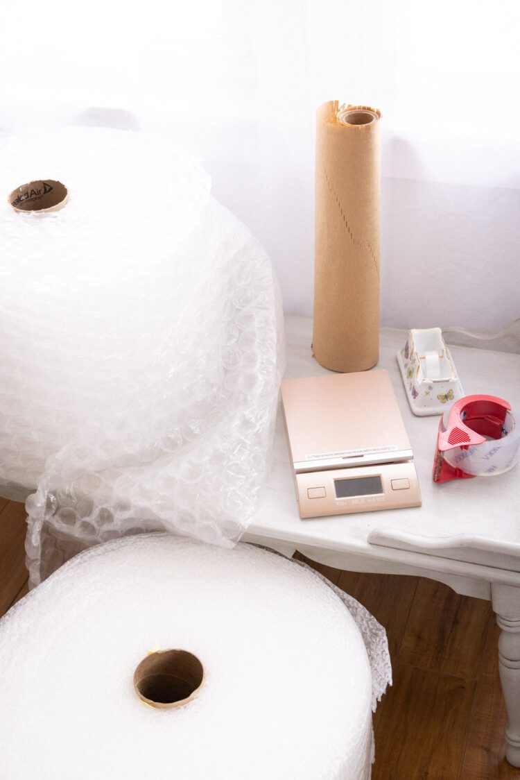 Packing supplies needed as a vintage reseller to ensure that items arrive safely to customers including bubble wrap, honeycomb paper, tape, and a postal scale.