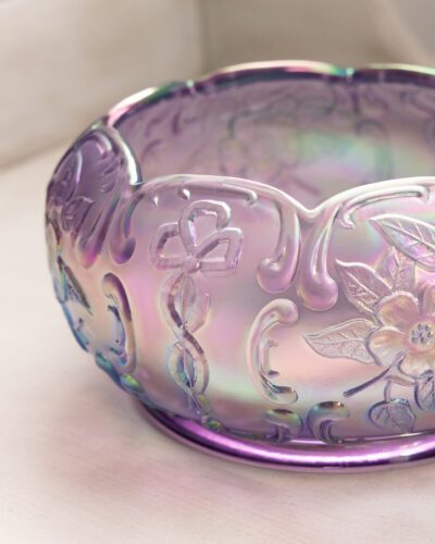 This exquisite Fenton purple floral bowl showcases Fenton's renowned craftsmanship with its mesmerizing iridescent finish and delicate floral patterns, bringing a touch of elegance to any space.